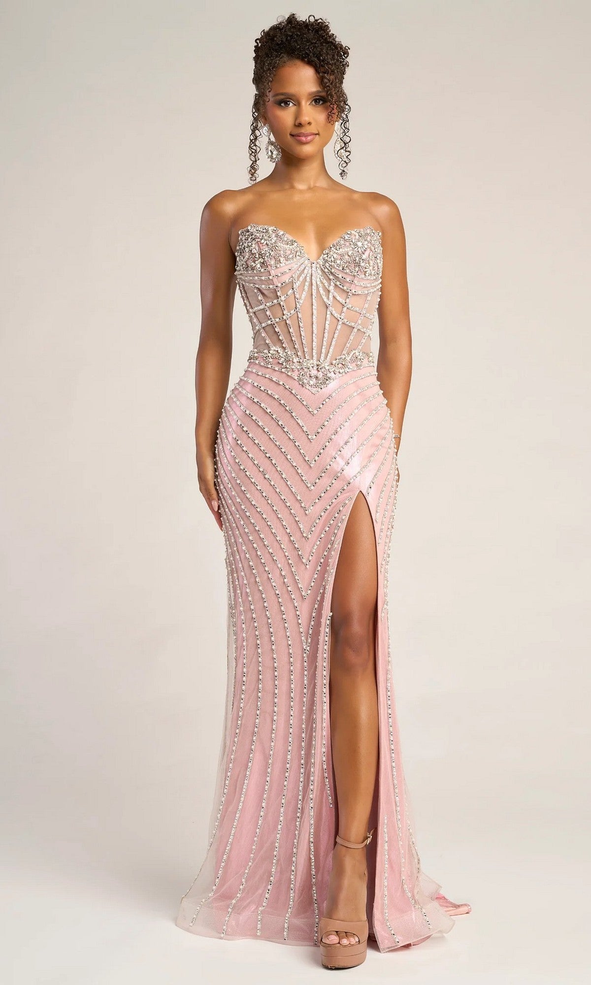 Woman wearing the Portia and Scarlett XO057 long formal dress in apricot, strapless with silver beadwork, sheer corset bodice, and high slit, standing against a plain background.